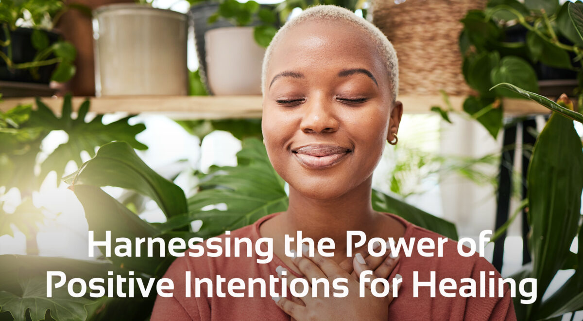 woman smiling with eyes shut, plants behind her and text below that says 'Harnessing the Power of Positive Intentions for Healing'