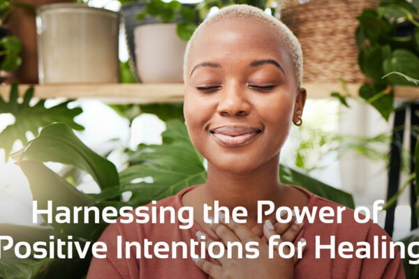 woman smiling with eyes shut, plants behind her and text below that says 'Harnessing the Power of Positive Intentions for Healing'